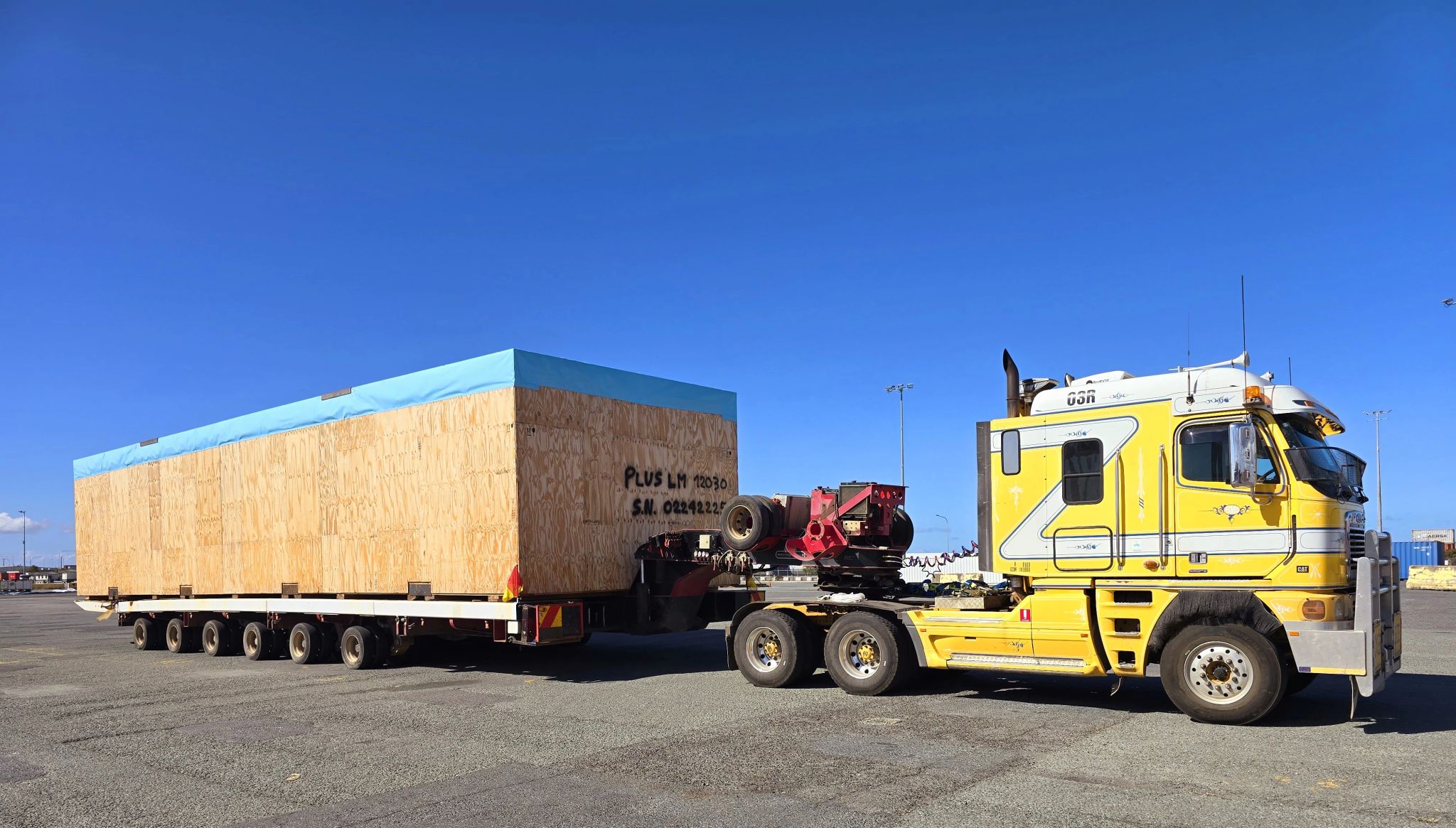 Yellow truck with a large wooden crate on a clear day