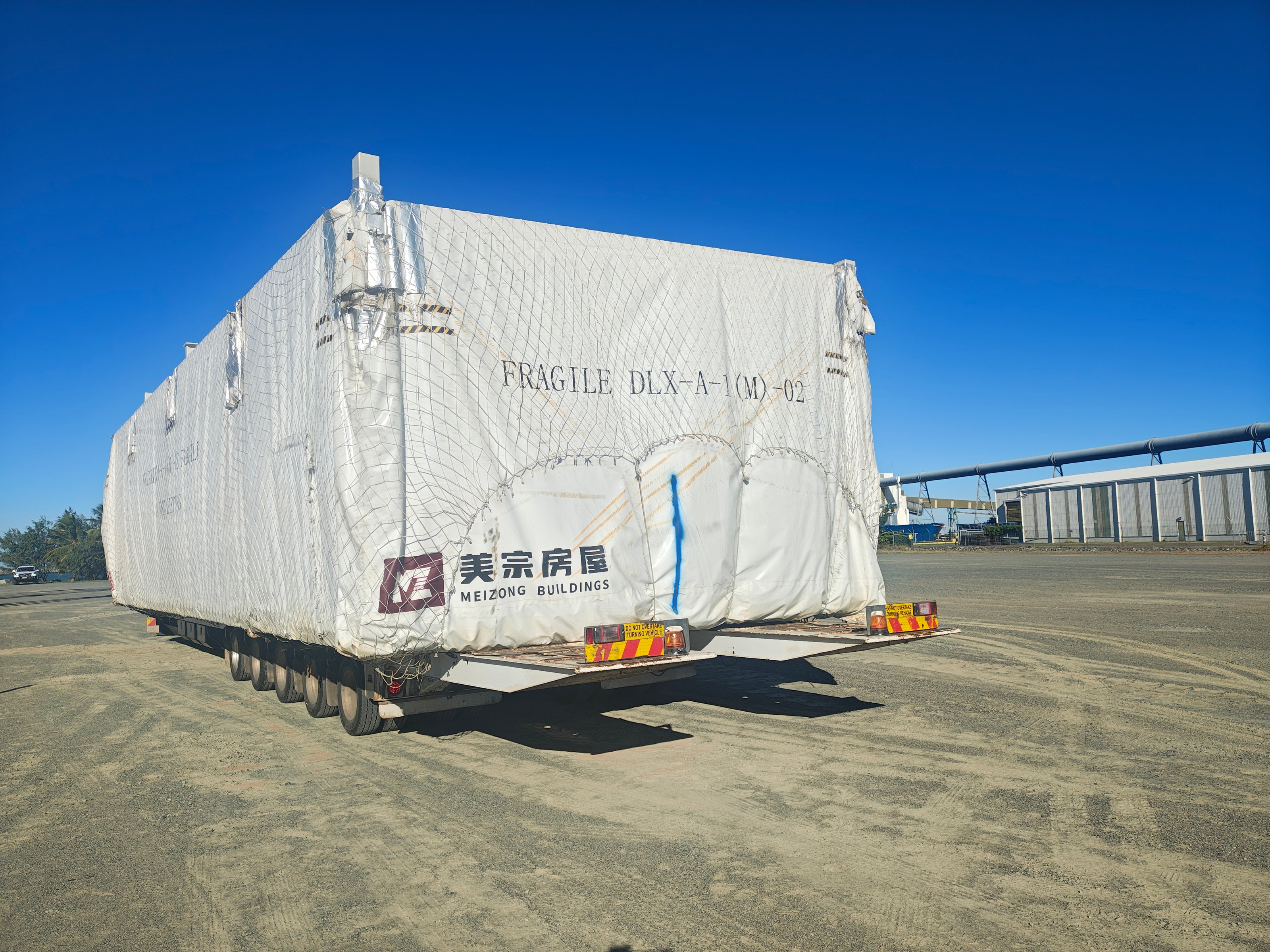 Trailer with a large white cargo container labeled 'Fragile' on a clear day.