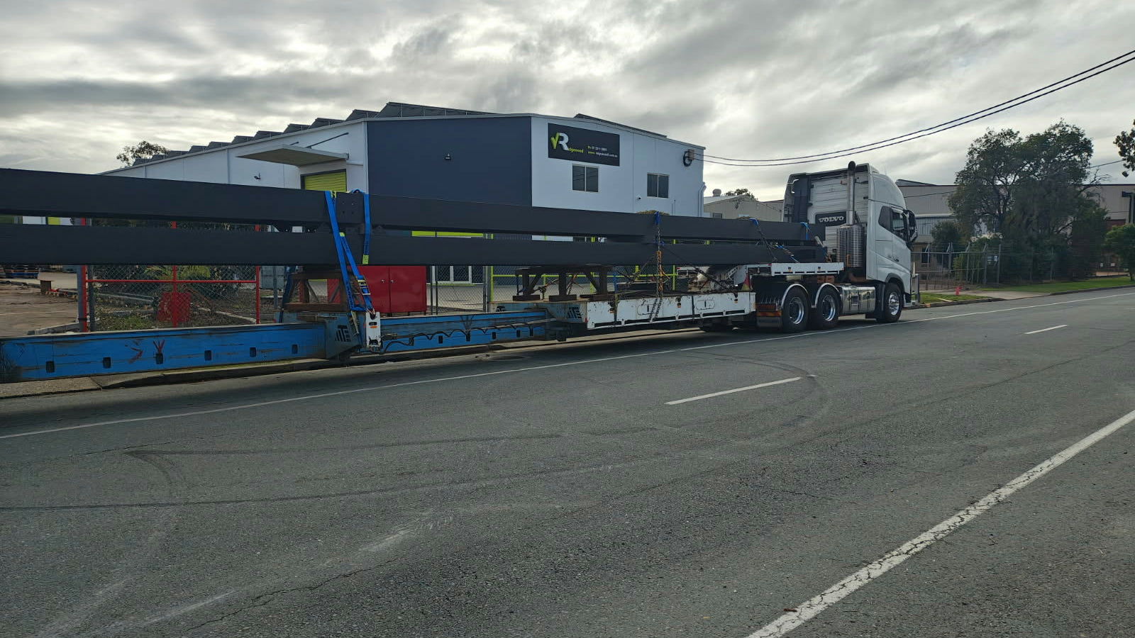 Low-loader truck on a road with a building in the background